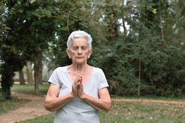 Übendes Yoga der älteren Frau draußen