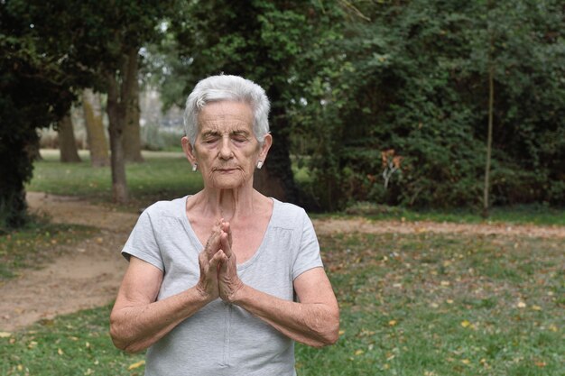 Übendes Yoga der älteren Frau draußen