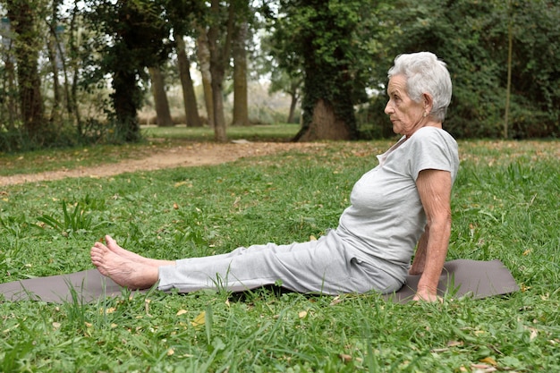 Übendes Yoga der älteren Frau draußen