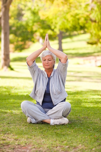 Übendes Yoga der älteren Frau im Park