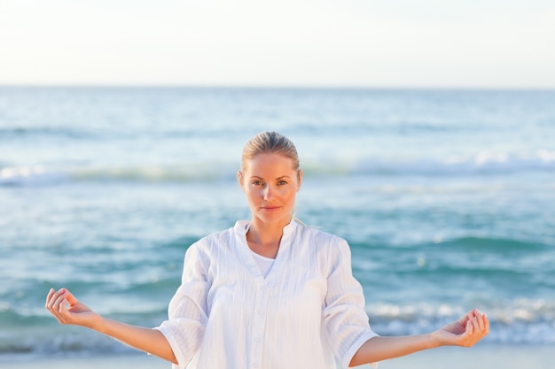 Übendes Yoga der aktiven Frau auf dem Strand