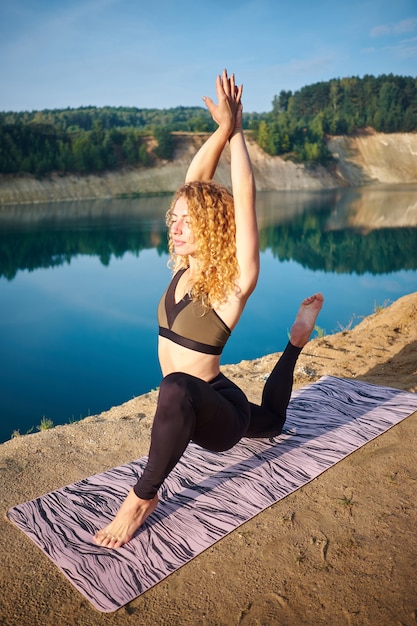 Übendes Yoga der attraktiven gelockten Frau der Rothaarigen draußen