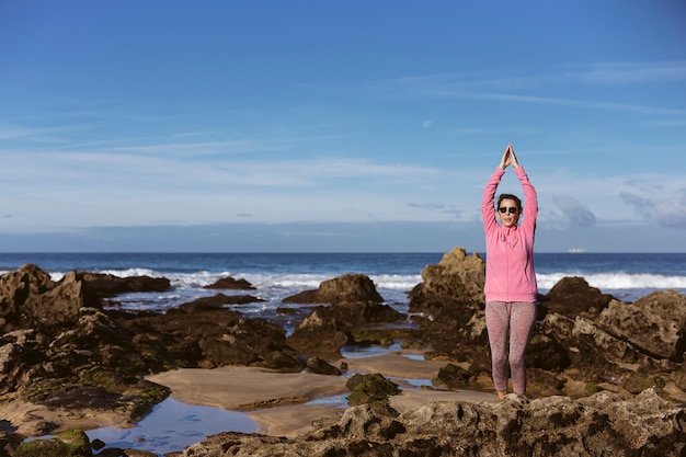 Übendes Yoga der Brunettefrau auf dem Strand