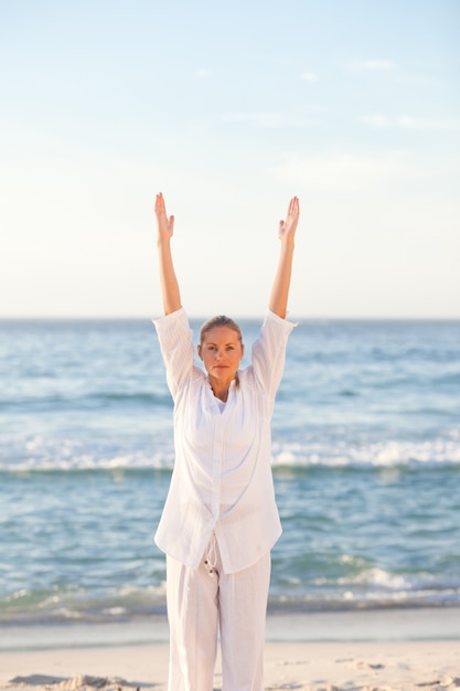Übendes Yoga der Frau am Strand
