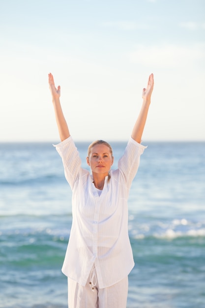 Übendes Yoga der Frau am Strand