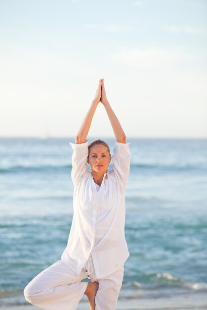 Übendes Yoga der Frau am Strand