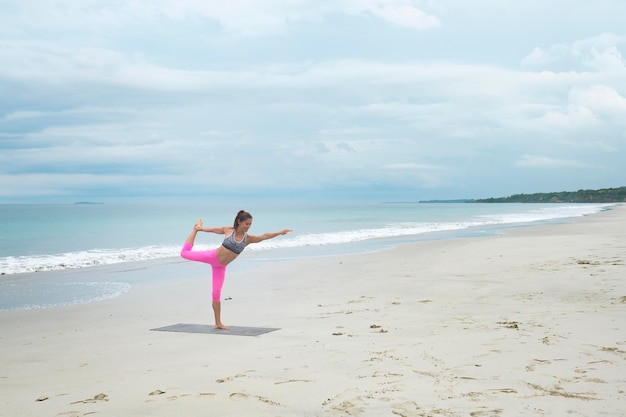 Übendes Yoga der Frau auf dem Strand