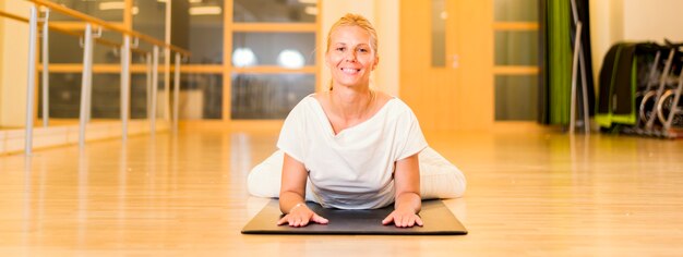 Übendes Yoga der Frau, das in Paschimottanasana-Position sitzt