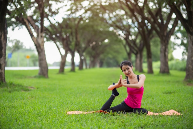 Übendes Yoga der jungen Frau im Park