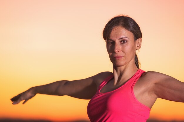 Übendes Yoga der jungen Schönheit bei Sonnenuntergang