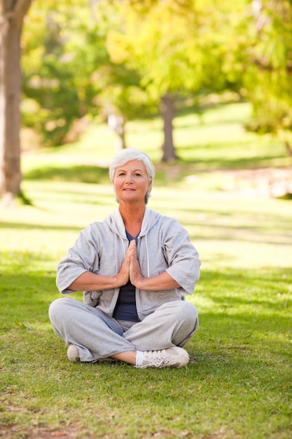 Übendes Yoga der reifen Frau im Park