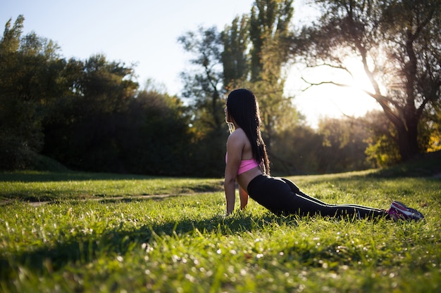 Übendes Yoga des jungen Mädchens auf der Natur im Park.