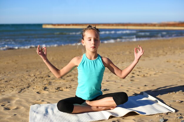 Übendes Yoga des Mädchens auf dem Strand.