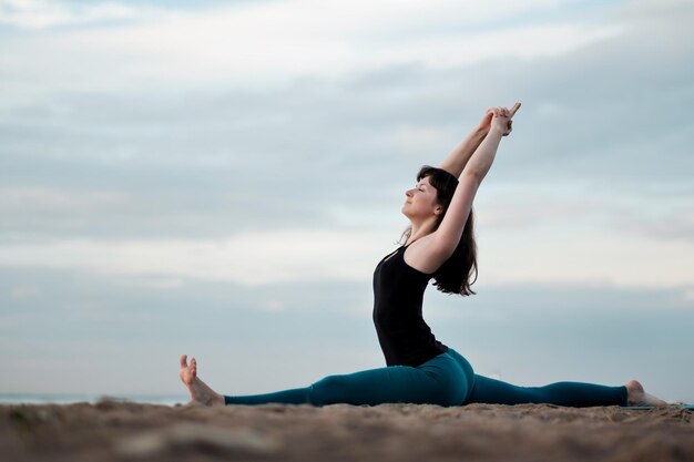 Übendes Yoga des Mädchens in der Natur hanumanasana Affenhaltung