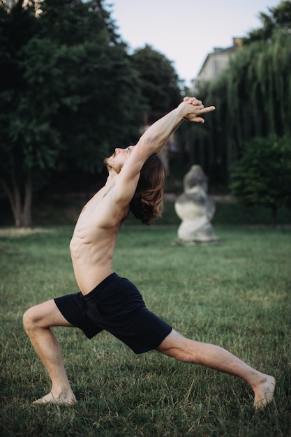 Übendes Yoga des sportlichen Mannes im Freien