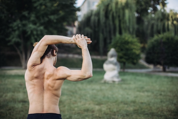 Übendes Yoga des sportlichen Mannes im Freien