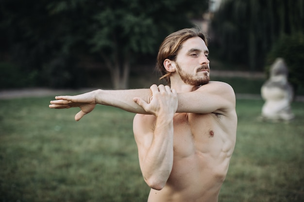 Übendes Yoga des sportlichen Mannes im Freien