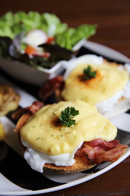 Benedict de huevo con tocino y patatas sobre fondo de madera