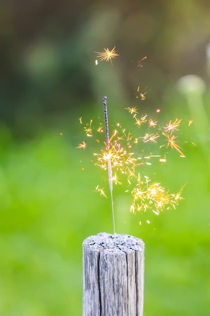 Una bengala ardiente sobre fondo de hierba verde. Detalle festivo de la fiesta de verano.