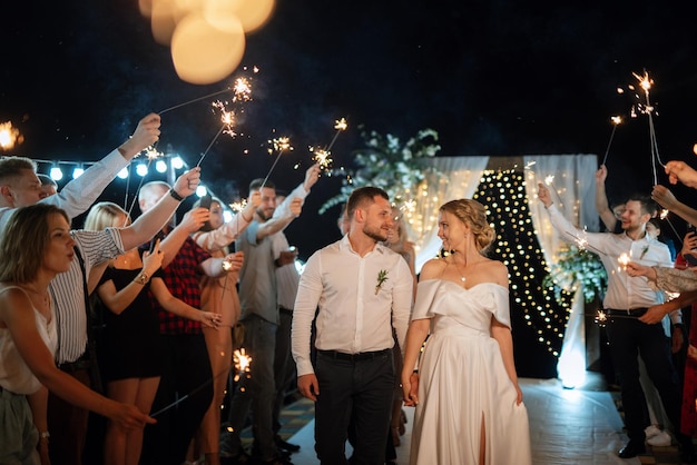 Bengalas en la boda de los recién casados en manos de alegres invitados.