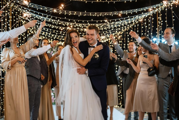 Bengalas en la boda de los recién casados en manos de alegres invitados.