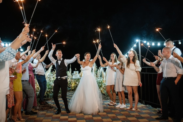 Bengalas en la boda de los recién casados en manos de alegres invitados.