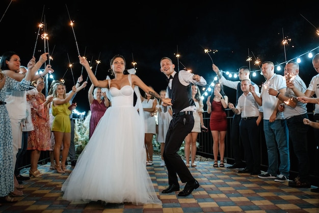 Bengalas en la boda de los recién casados en manos de alegres invitados.