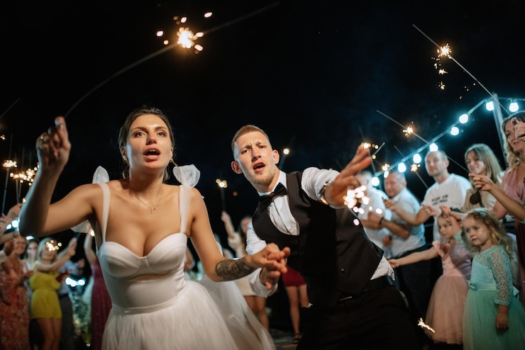Foto bengalas en la boda de los recién casados en manos de alegres invitados.