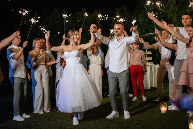 Bengalas en la boda de los recién casados en manos de alegres invitados.