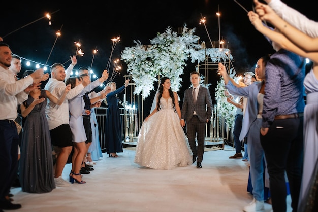 Bengalas en la boda de los recién casados en manos de alegres invitados.