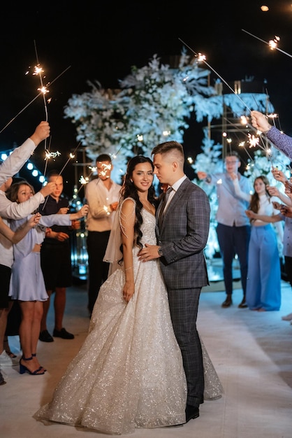 Bengalas en la boda de los recién casados en manos de alegres invitados.