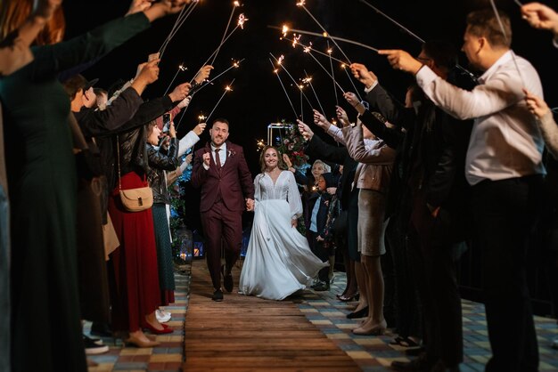 Bengalas en la boda de los recién casados en manos de alegres invitados.