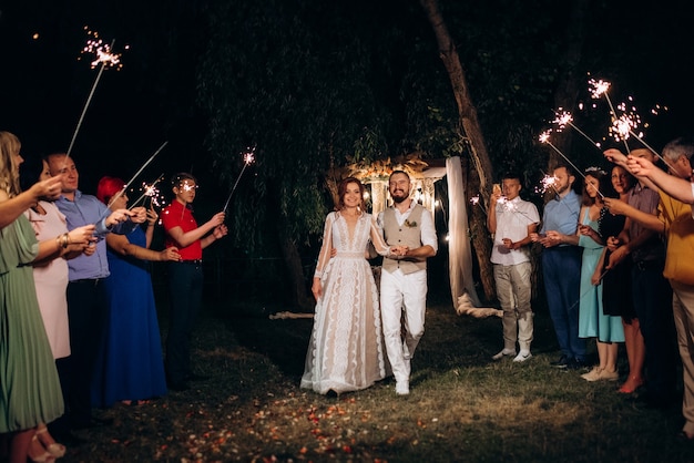 Bengalas en la boda de los recién casados en manos de alegres invitados.