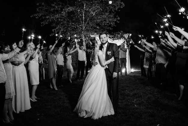 Bengalas en la boda de los recién casados en manos de alegres invitados.