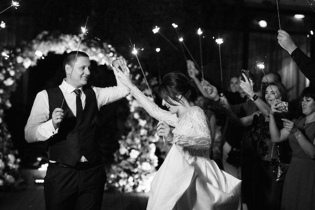 Bengalas en la boda de los recién casados en manos de alegres invitados.