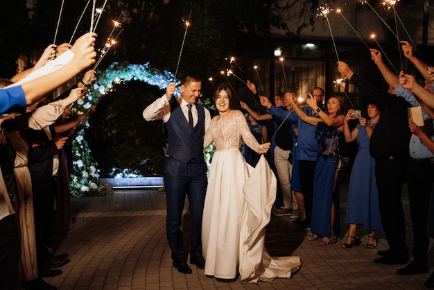 Bengalas en la boda de los recién casados en manos de alegres invitados.