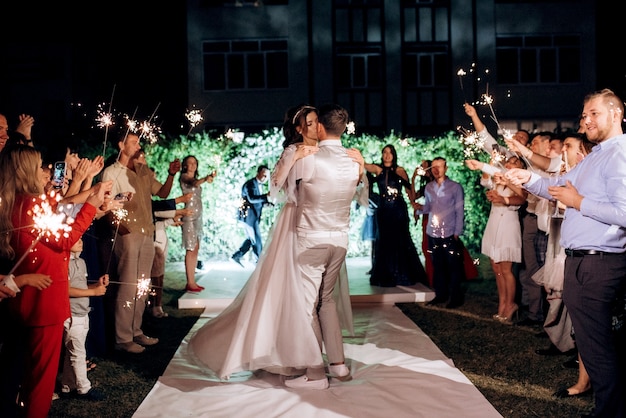 Bengalas en la boda de los recién casados en manos de alegres invitados.