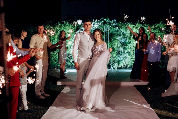 Bengalas en la boda de los recién casados en manos de alegres invitados.