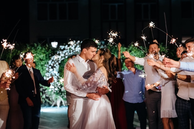 Bengalas en la boda de los recién casados en manos de alegres invitados.