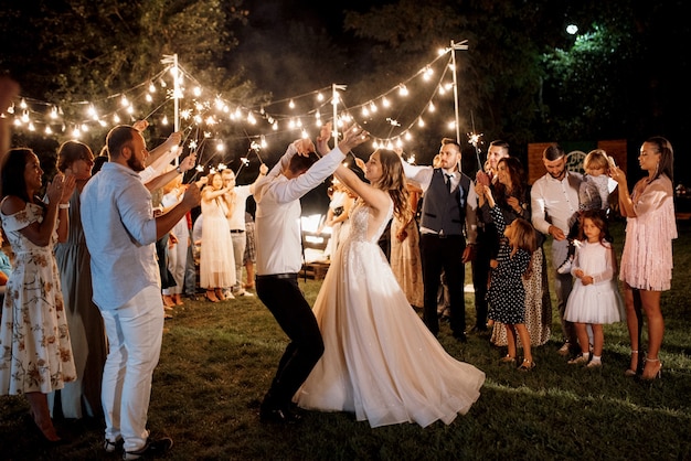 Bengalas en la boda de los recién casados en manos de alegres invitados.