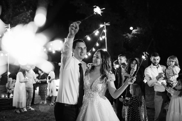 Bengalas en la boda de los recién casados en manos de alegres invitados.