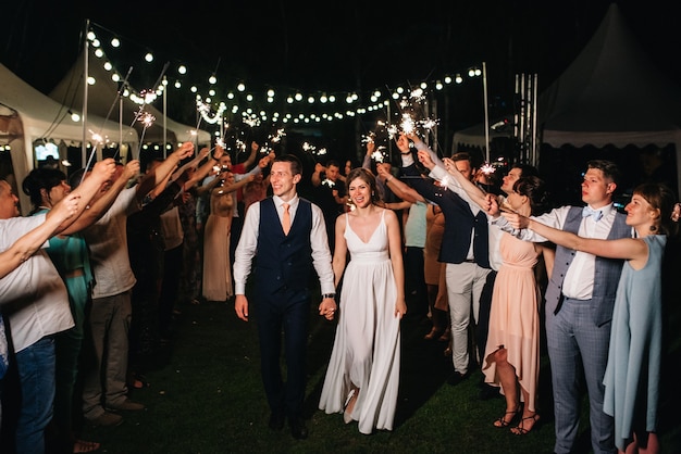 Bengalas en la boda de los recién casados en manos de alegres invitados.