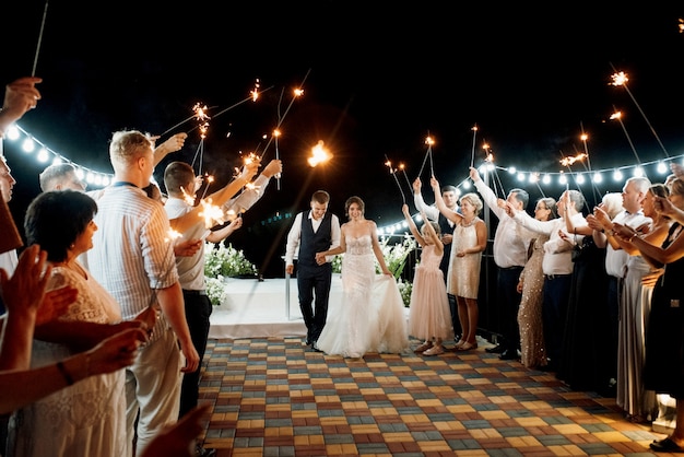 Bengalas en la boda de los recién casados en manos de alegres invitados.