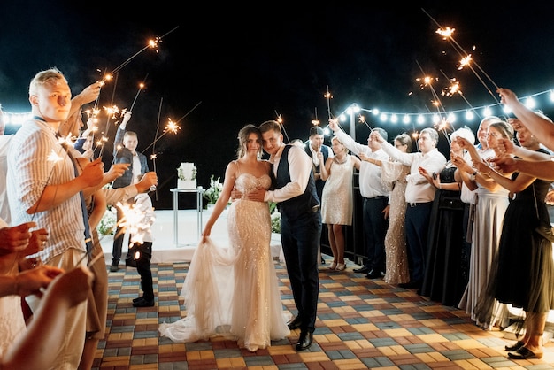 Bengalas en la boda de los recién casados en manos de alegres invitados.