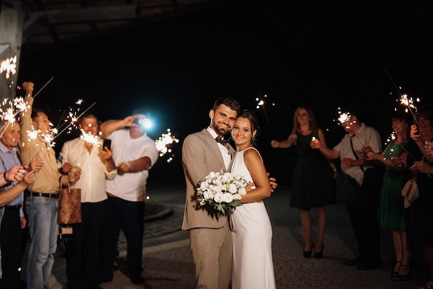 Bengalas en la boda de los recién casados en manos de alegres invitados.