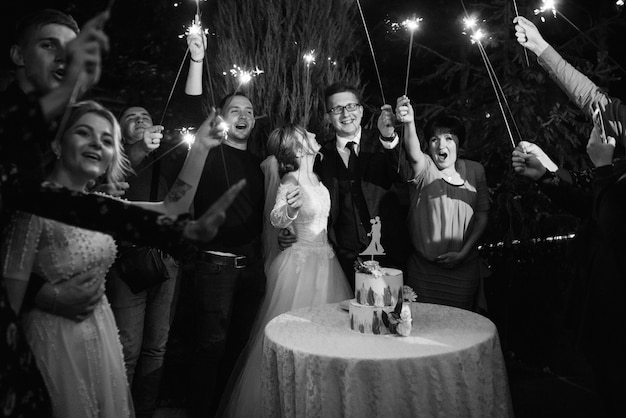 Foto bengalas en la boda de los recién casados en manos de alegres invitados.