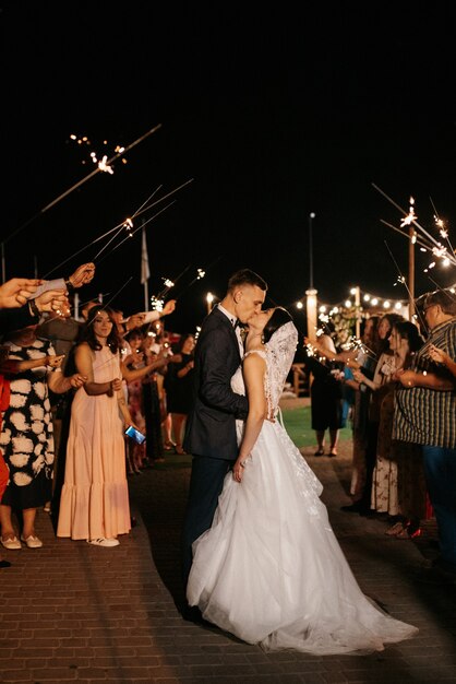 Bengalas en la boda de los recién casados en manos de alegres invitados.