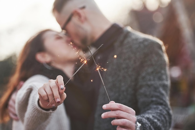 Con bengalas en las manos. Feliz pareja multirracial juntos al aire libre en la ciudad.