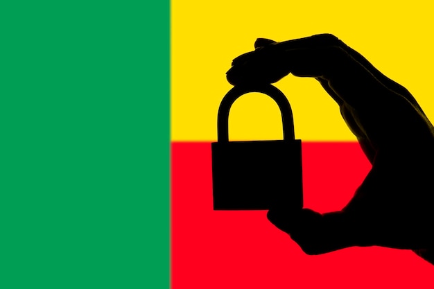 Benin-Sicherheit Silhouette einer Hand, die ein Vorhängeschloss über der Nationalflagge hält