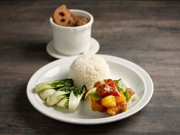 Bento de arroz de cerdo agridulce servido en un plato aislado en la vista lateral de la mesa